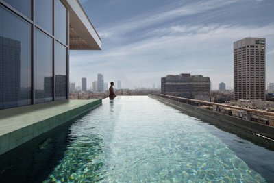 Piscina de borda infinita em prédio com revestimento azul aplicado no fundo a laterais.